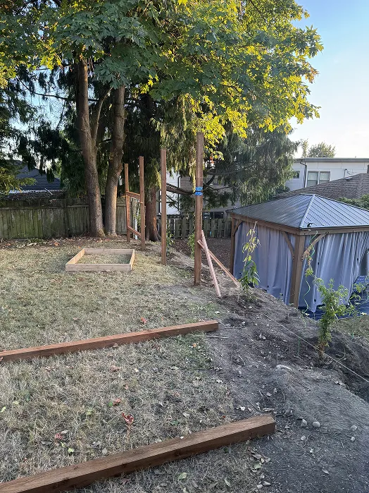 Fence post holes dug along the back of the yard with posts set in concrete