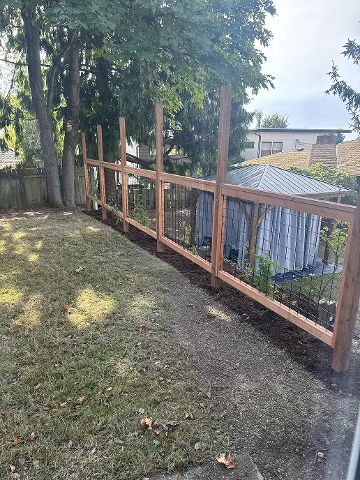 Top horizontal runners installed across the fence posts above the hog wire section