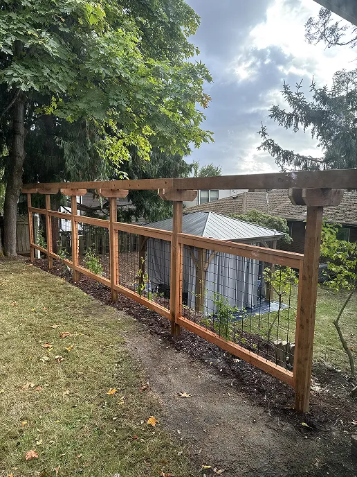 Completed fence with decorative diagonal crossbar lattice topper installed, backyard visible behind it